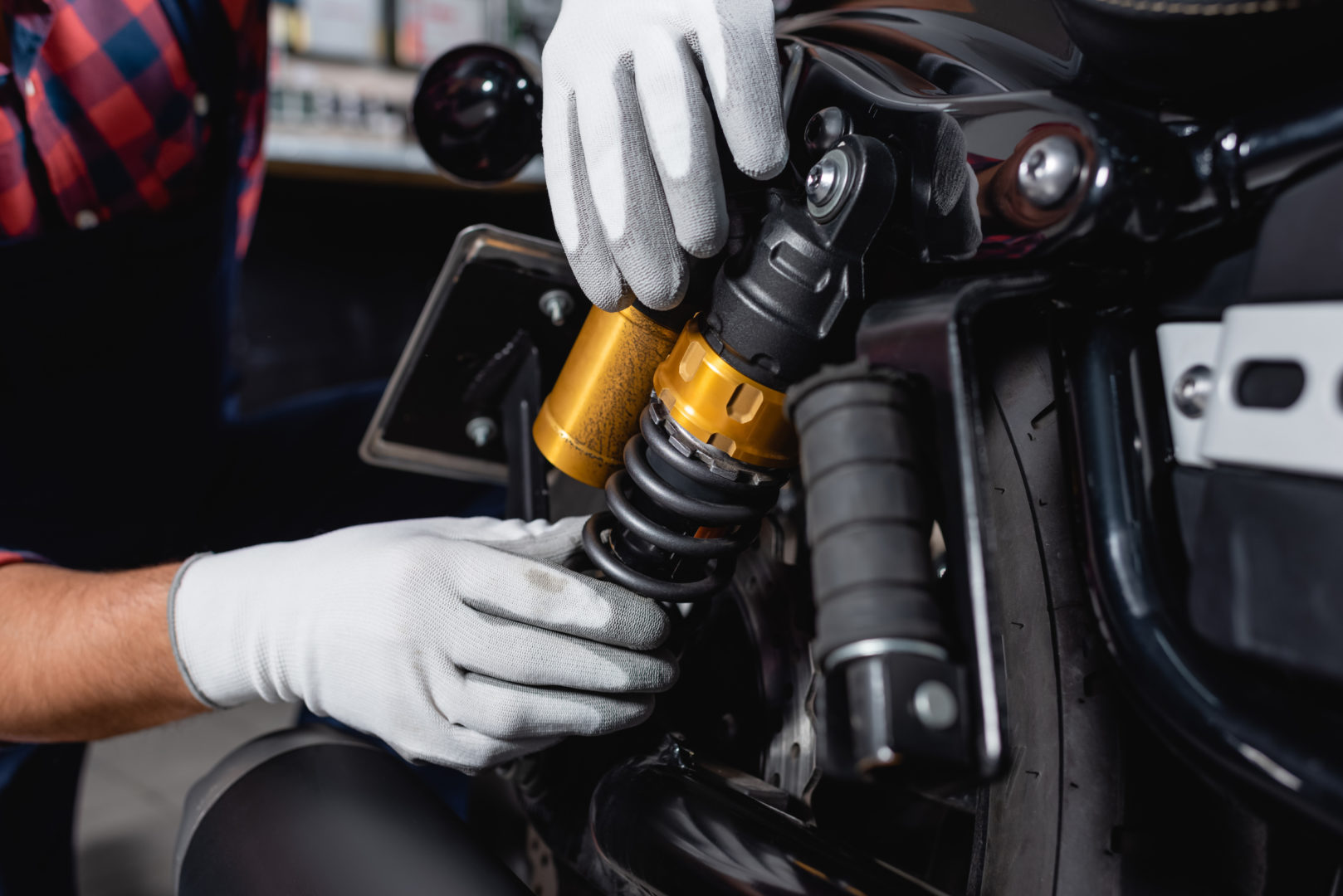 cropped view of mechanic checking shock absorber of motorcycle i